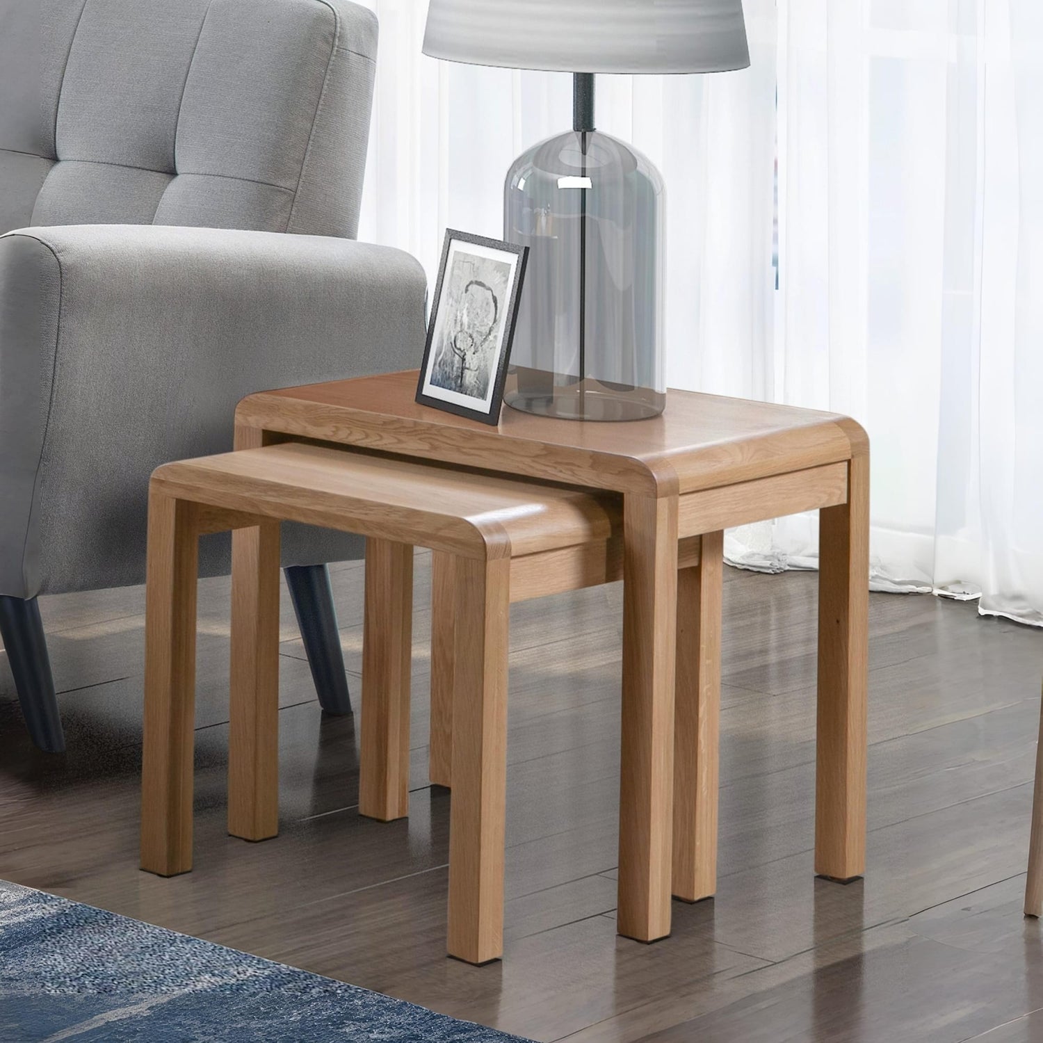 Wooden side tables in a living room setting with a gray armchair and lamp.
