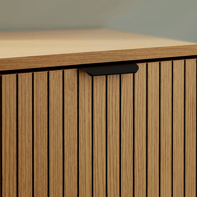 Wooden cabinet with a light brown finish and a dark handle on a neutral background