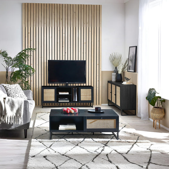 Modern living room with a television, coffee table, and decorative items.