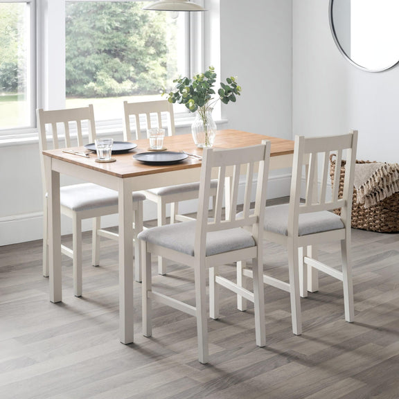 Dining table set with chairs in a room with large windows.