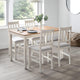 Dining table set with chairs in a room with large windows.