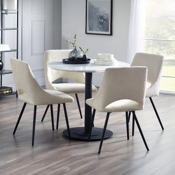 Dining room with a round table and four chairs on a wooden floor.