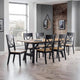 Dining room with a wooden table and chairs against a brick wall.