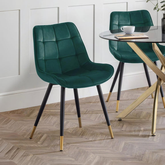 Green upholstered chairs with gold legs in a room with a table and decor.