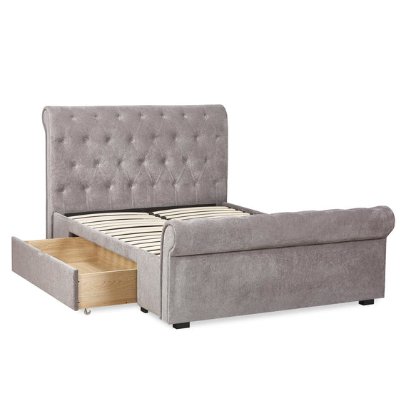 Gray upholstered bed with tufted headboard and open drawer on a white background