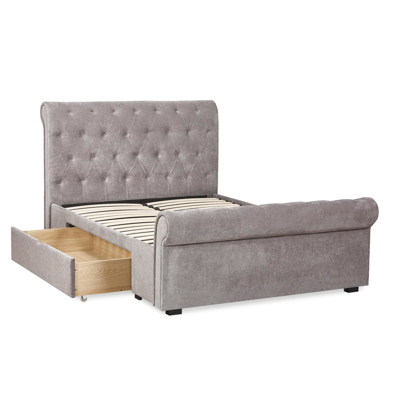Gray upholstered bed with tufted headboard and open drawer on a white background