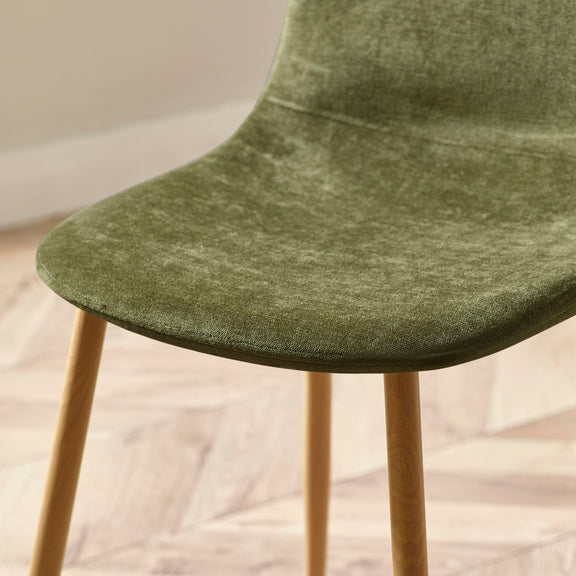 Green upholstered chair with wooden legs on a light wooden floor.