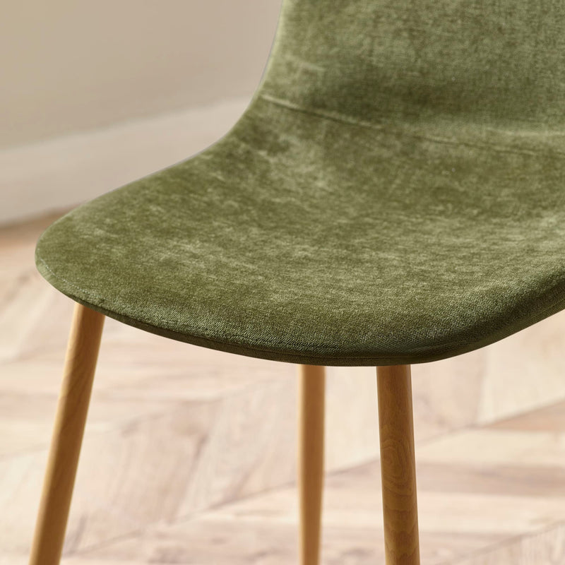 Green upholstered chair with wooden legs on a light wooden floor.