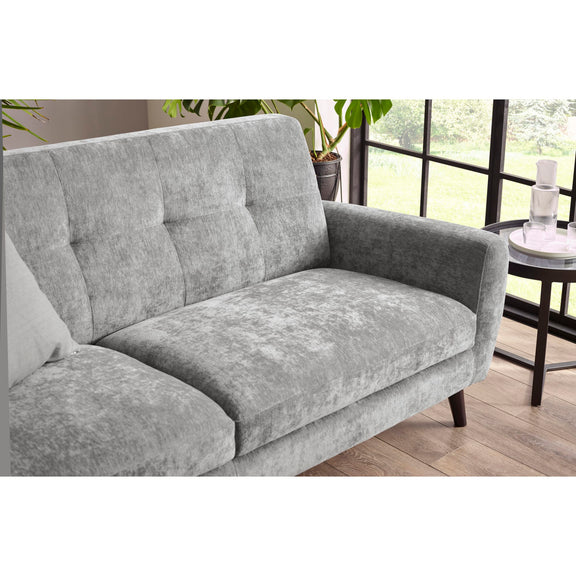 Gray sofa in a living room setting with a window and plants in the background.