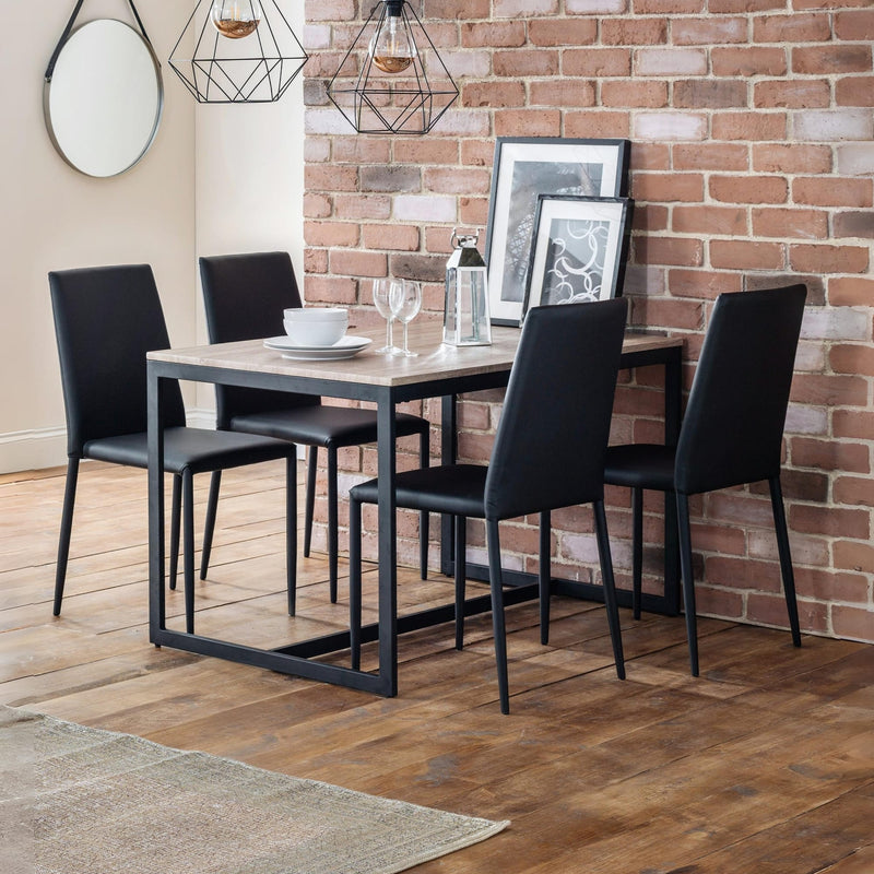 Dining area with a table and four black chairs against a brick wall.