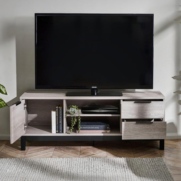 TV on a wooden stand with open cabinet doors displaying books and plants in a room.