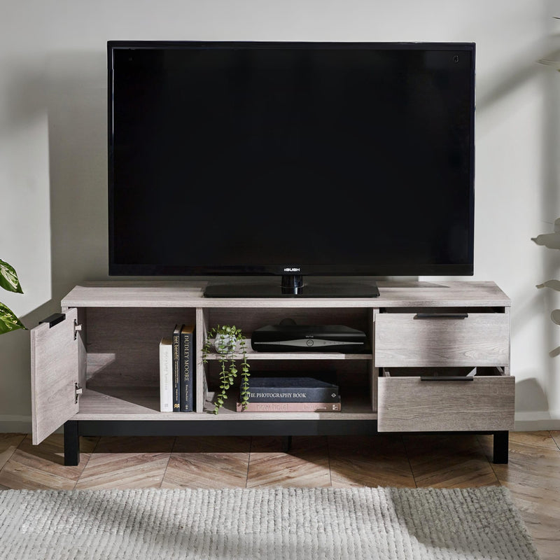 TV on a wooden stand with open cabinet doors displaying books and plants in a room.