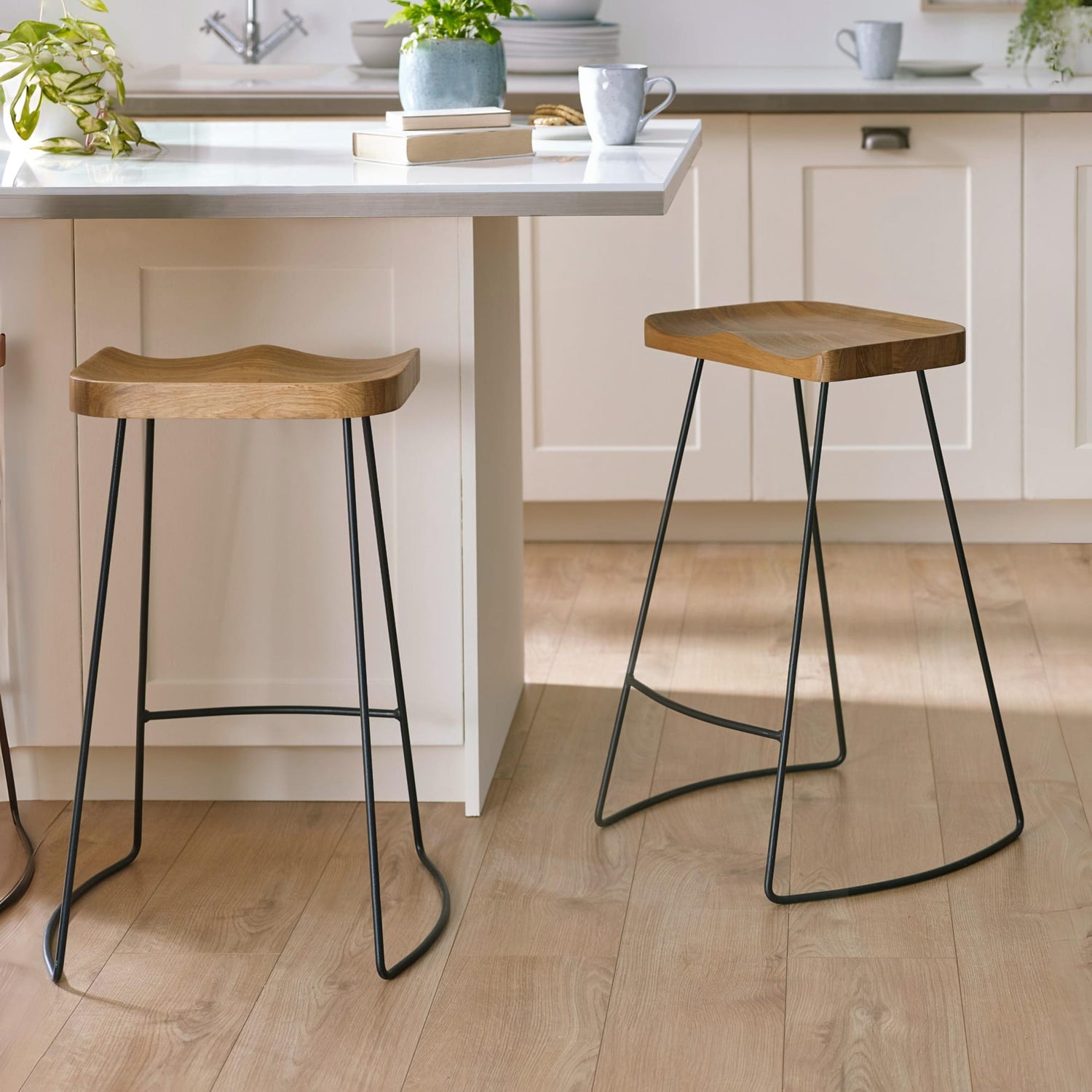 Two wooden stools with black metal legs in a kitchen setting.