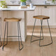 Two wooden stools with black metal legs in a kitchen setting.