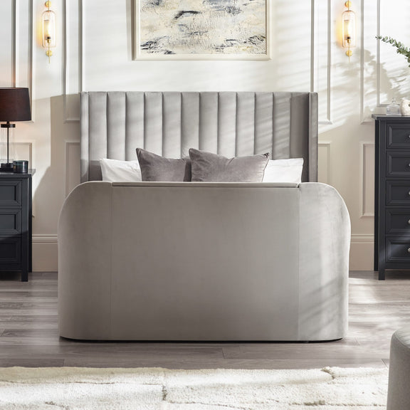 Gray upholstered bed in a stylish bedroom with abstract art on the wall.