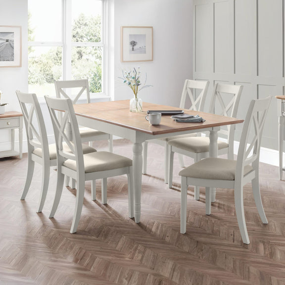 Dining room with a wooden table and white chairs on a wooden floor.