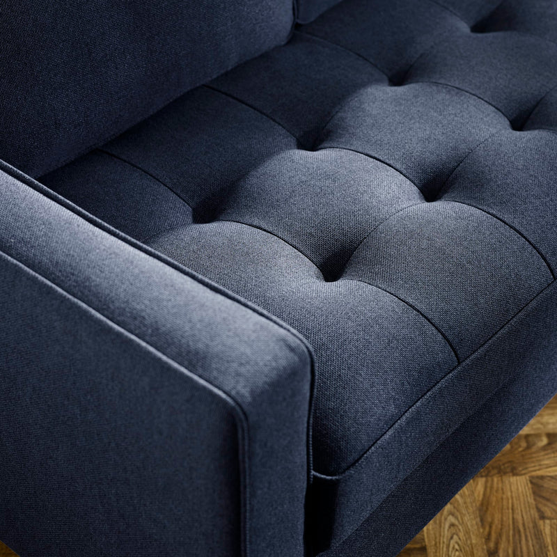 Close-up of a dark blue upholstered chair with tufted backrest.