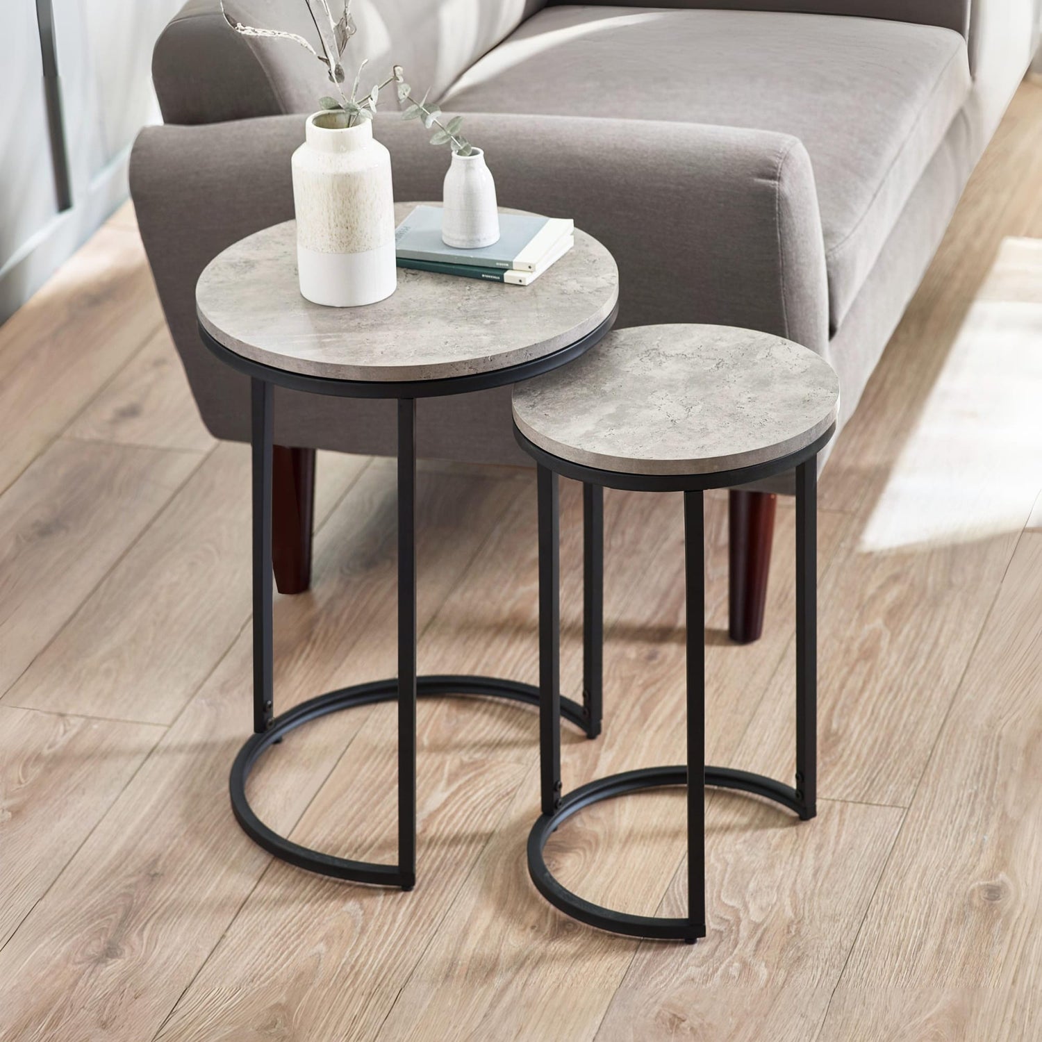 Two round side tables with marble-like tops and black metal legs in a living room setting.