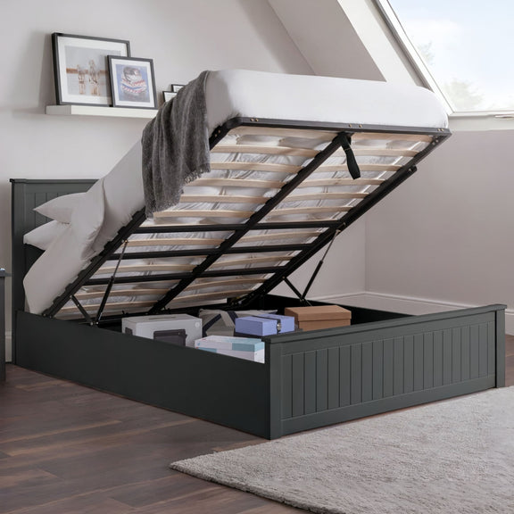 Black bed frame with storage compartment open in a room with a window and framed pictures on the wall.
