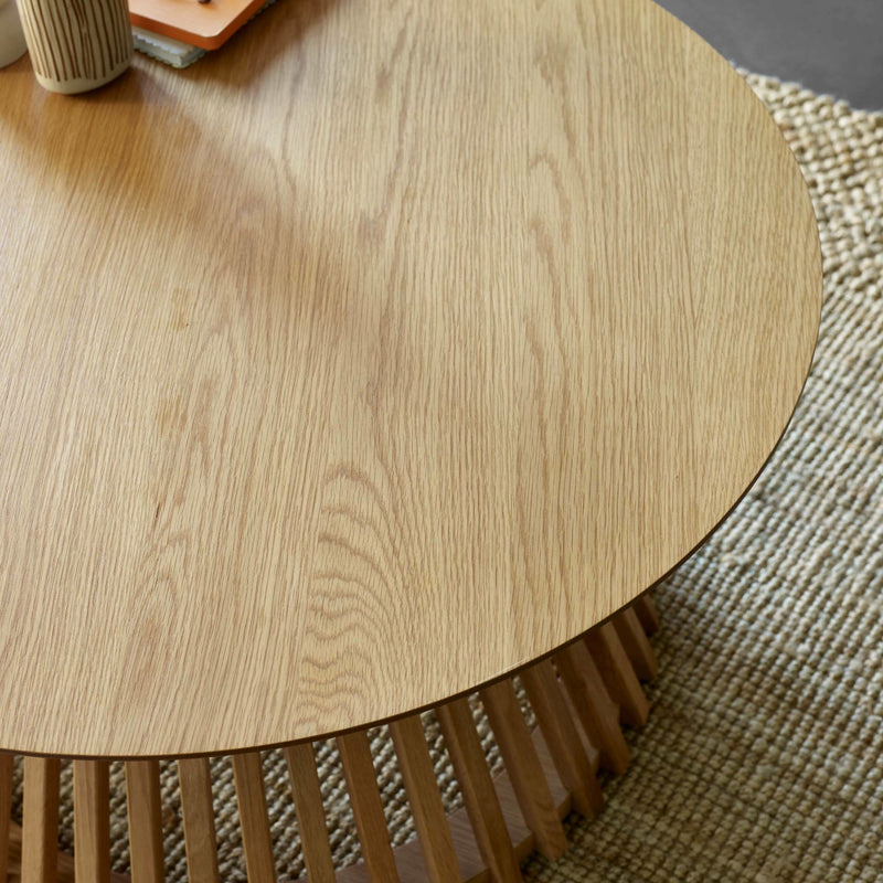 Round wooden table with a textured surface on a woven mat
