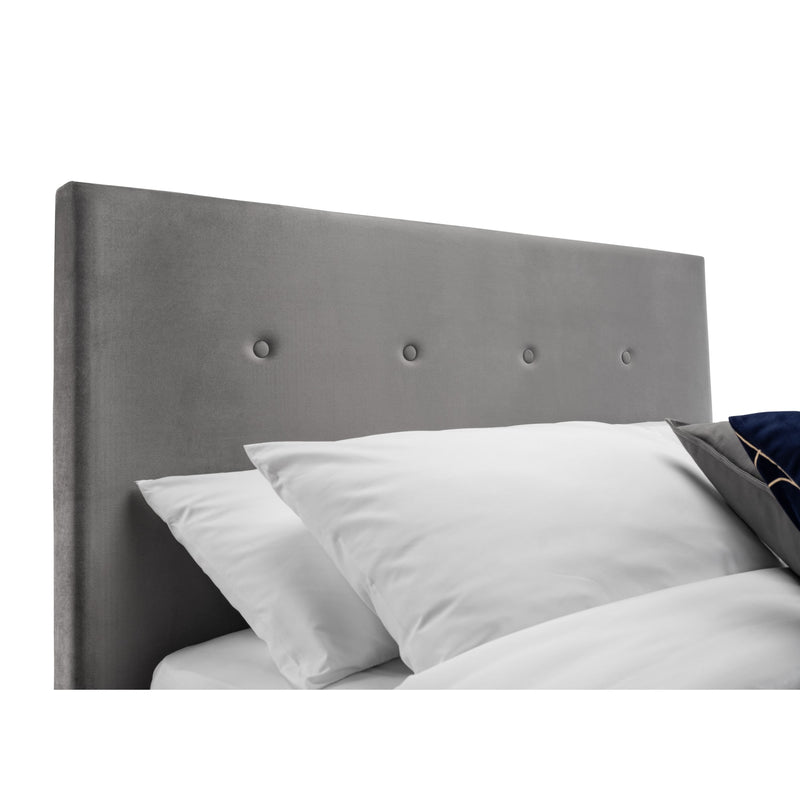 Gray upholstered headboard with white pillows on a white background
