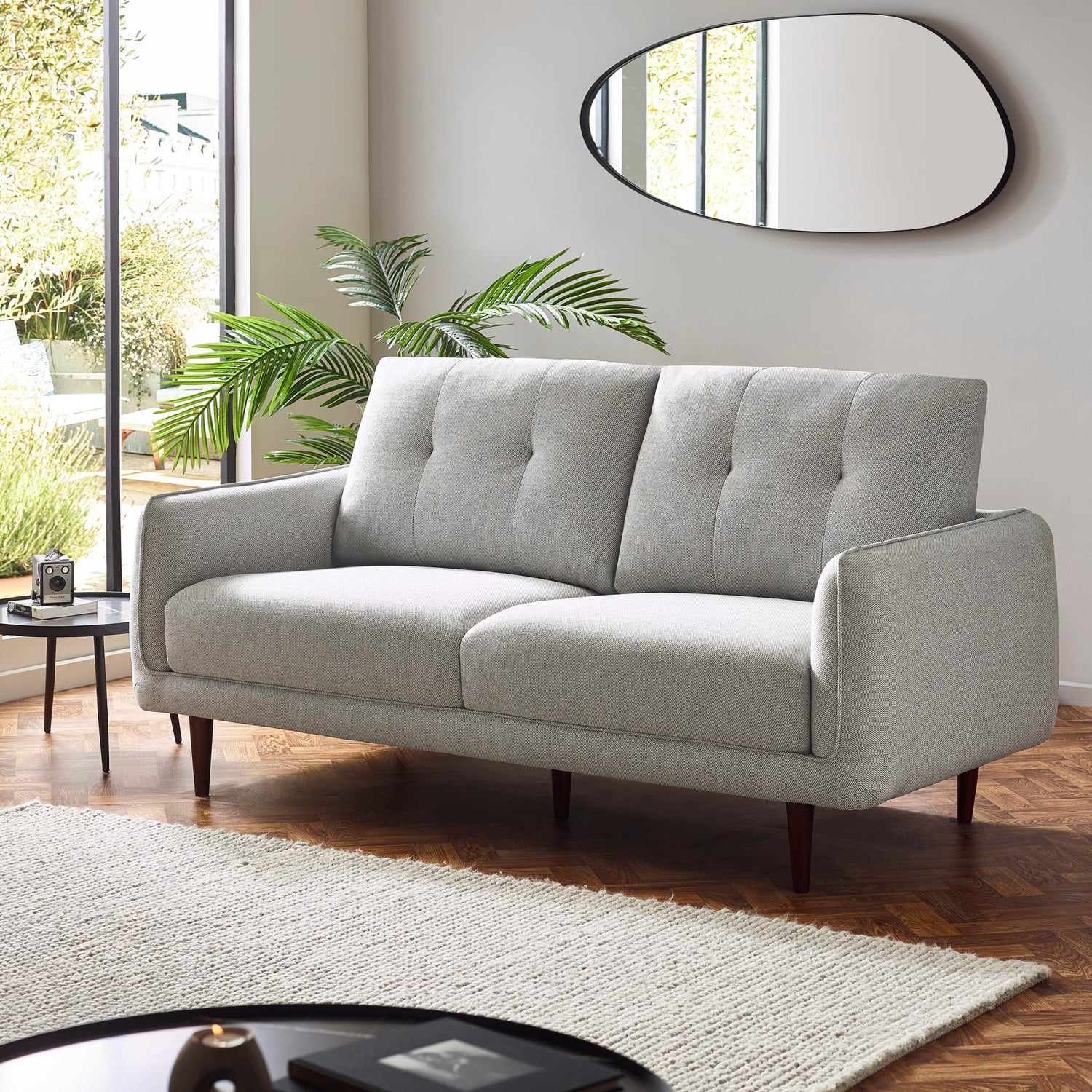 Gray sofa in a living room with a mirror and plants