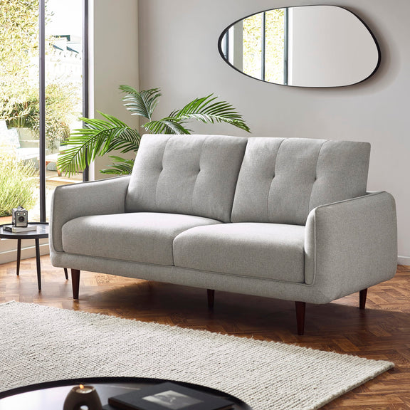 Gray sofa in a living room with a mirror and plants