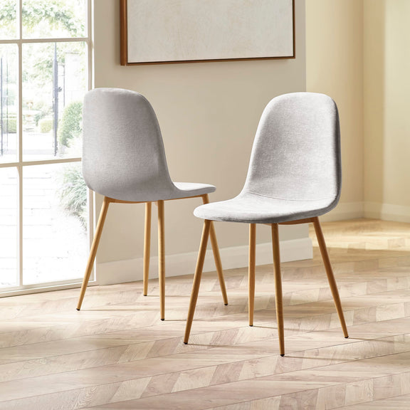 Two gray chairs with wooden legs in a room with a large window.
