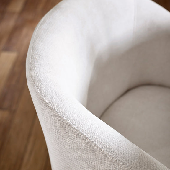 Close-up of a beige upholstered chair on a wooden floor