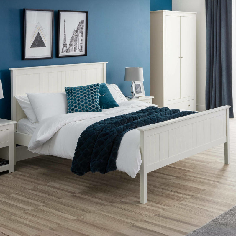 Bedroom with white bed, blue accent pillows, and a wardrobe.