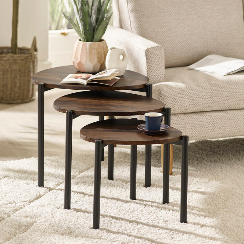 Set of three wooden nesting tables in a living room setting with a cup and book on top.