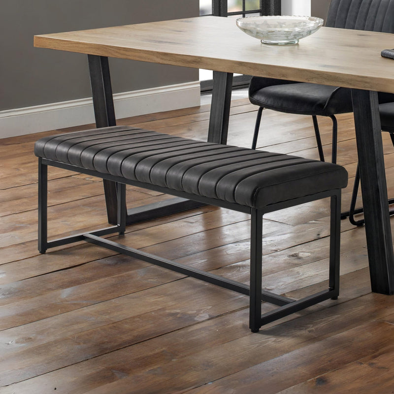 Black bench with striped pattern in front of a wooden dining table.