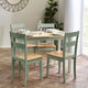 Dining table set with four chairs in a room with a plant and window.