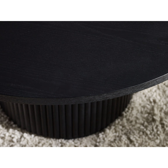 Close-up of a black round table with a textured base on a carpeted floor.