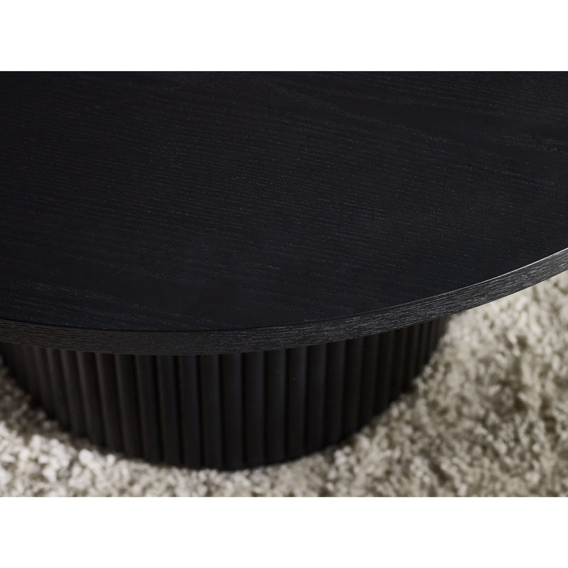 Close-up of a black round table with a textured base on a carpeted floor.