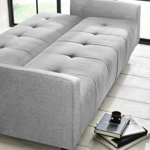 Gray upholstered bed in a room with a window