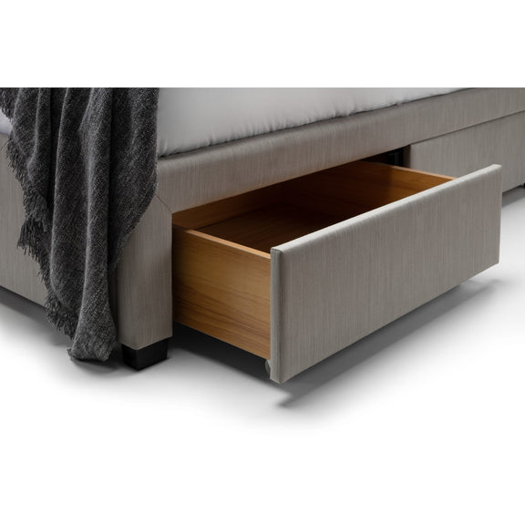Gray upholstered bed with an open wooden drawer on a white background