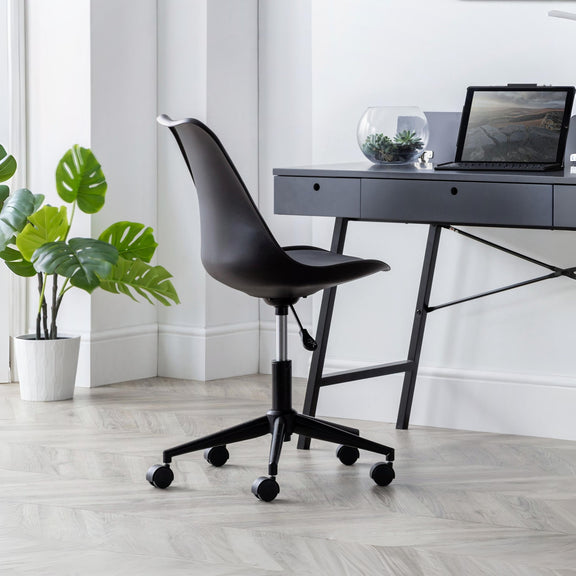 Black office chair in front of a desk with a laptop and plants in a bright room.