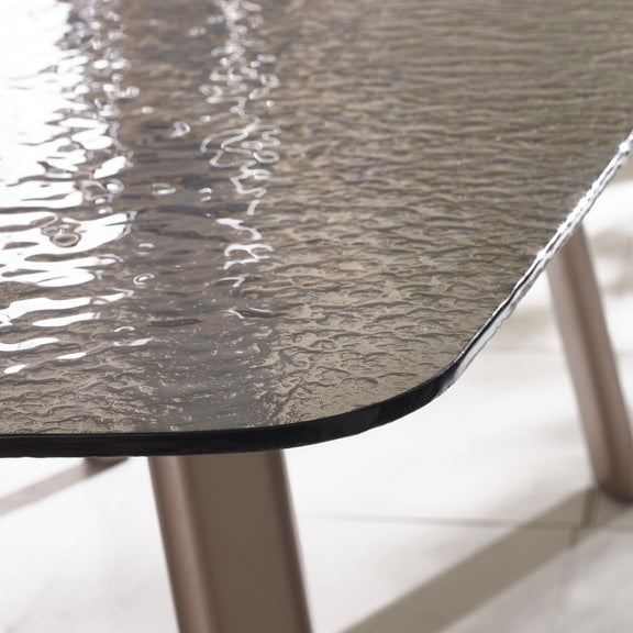Close-up of a textured glass table top with metallic legs on a light background