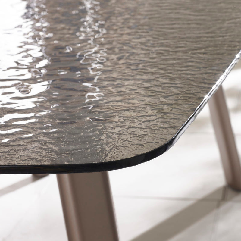 Close-up of a textured glass table top with metallic legs on a light background