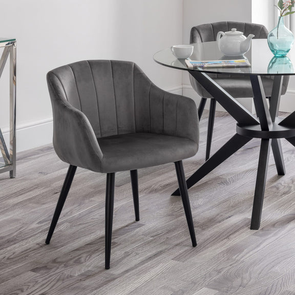 Gray upholstered chair in a modern dining room setting with a glass table.