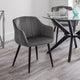 Gray upholstered chair in a modern dining room setting with a glass table.
