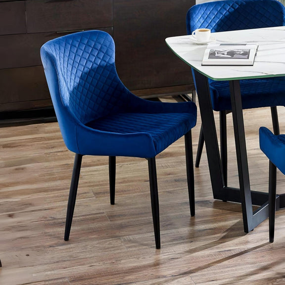 Blue chairs with quilted design around a dining table on a wooden floor.