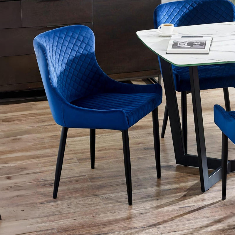 Blue chairs with quilted design around a dining table on a wooden floor.