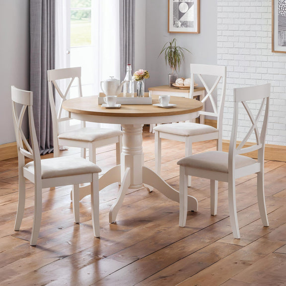 Dining room with round wooden table and white chairs on a wooden floor.
