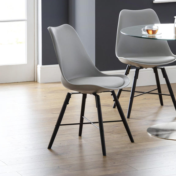 Modern gray chairs with black legs in a room with a glass table and window.