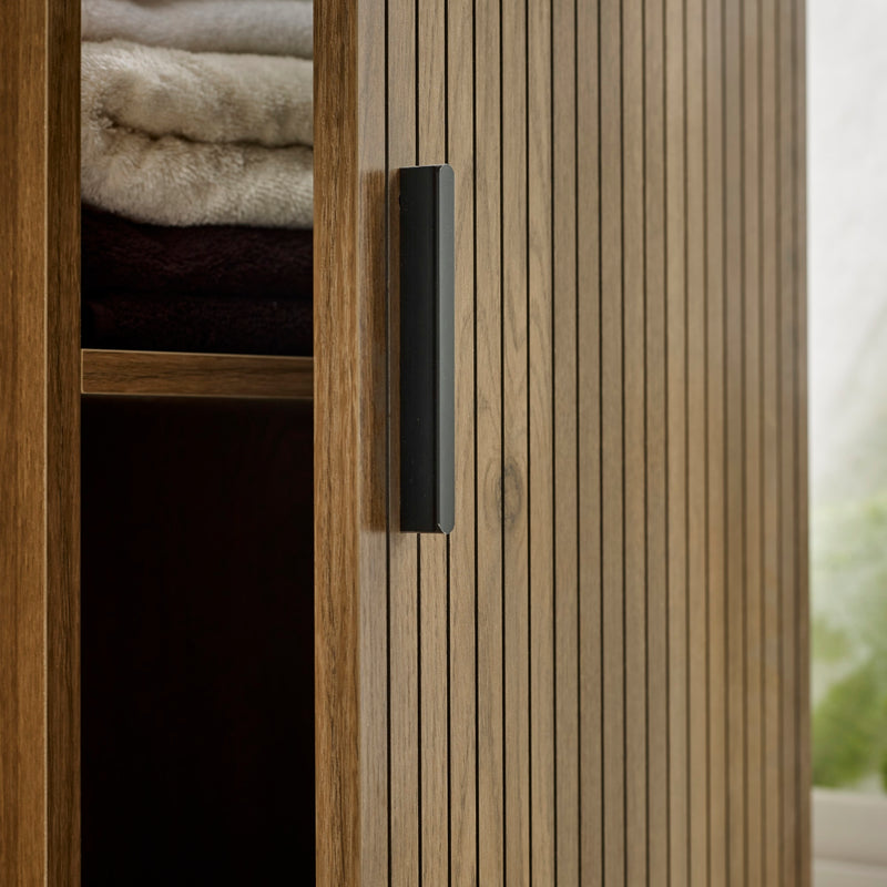 Wooden wardrobe with a black handle and folded clothes inside