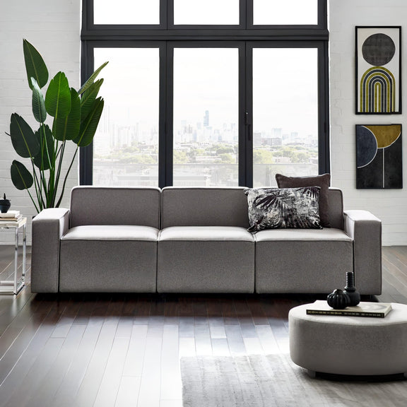 Modern living room with a gray sofa, round coffee table, and cityscape view.