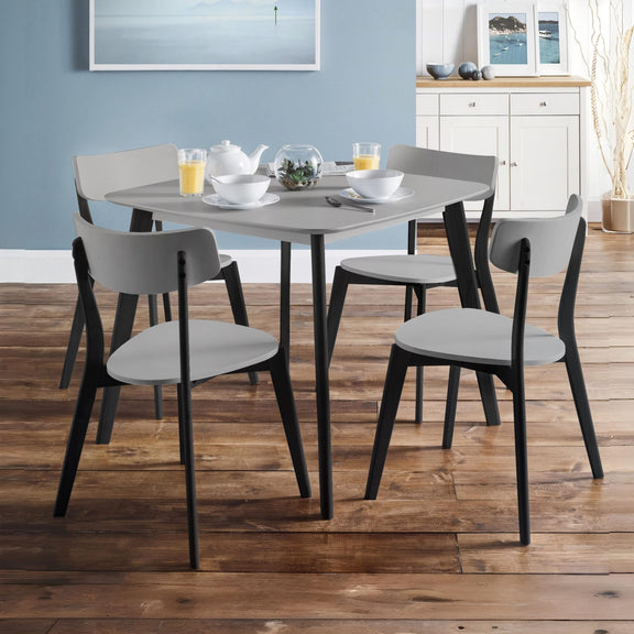 Dining table set with chairs in a room with wooden flooring and light blue walls.