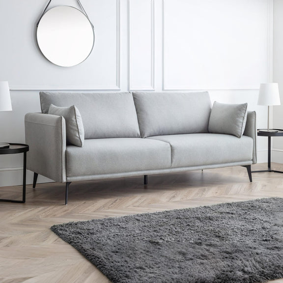Gray sofa in a modern living room with a rug and side tables.